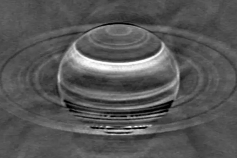 Radio image of Saturn taken with the VLA in May 2015, with the brighter radio emissions from Saturn and its rings subtracted to enhance the contrast in the fainter radio emissions between the various latitudinal bands in the atmosphere. Since ammonia blocks radio waves, the bright features indicate areas where ammonia is depleted and the VLA could see deeper in the atmosphere. The broad bright band at northern latitudes is the aftermath of the 2010 storm on Saturn, which apparently depleted ammonia gas just below the ammonia-ice cloud, which is what we see with the naked eye. المصدر: R. J. Sault and I. de Pater