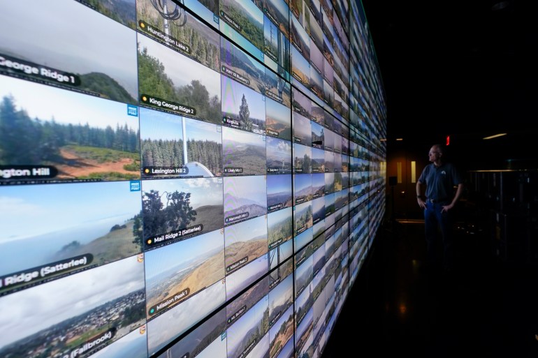 Falco Kuester, a researcher at ALERTCalifornia, a program run by the University of California San Diego, looks at live feeds from some of the program's cameras, Monday, Sept. 18, 2023, in San Diego. California's main firefighting agency, Cal Fire, in July started trying out an artificial intelligence system that looks for smoke from more than 1,000 mountaintop cameras feeds. (AP Photo/Gregory Bull)