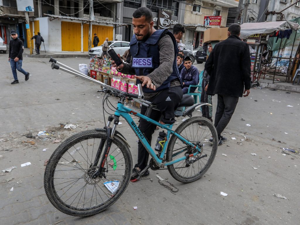 بساق واحدة وعلى دراجة هوائية.. فلسطيني يوثق جرائم إسرائيل بغزة