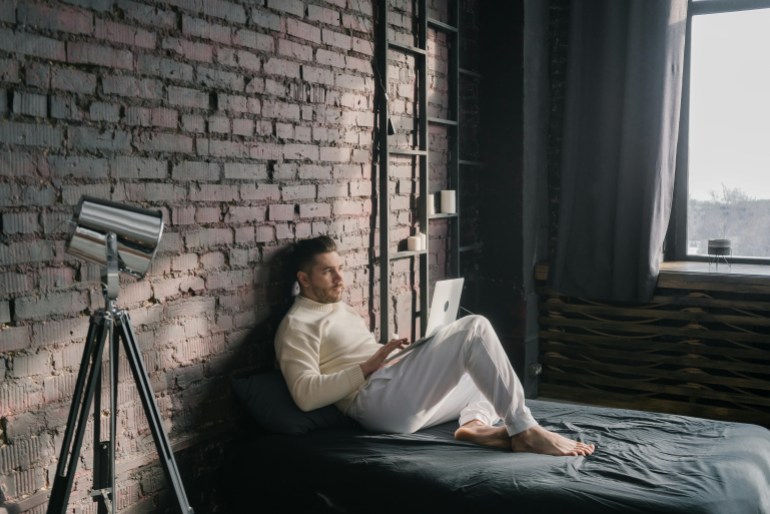 A Man Using a Laptop while Lying on the Bed