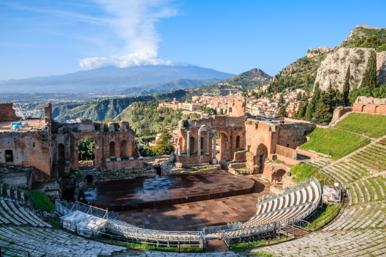 The Greek theatre with smoking Mount Etna volcano in the background, Taormina, Sicily, Italy.