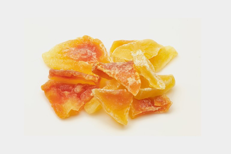 Pile of freeze-dried papaya fruit slices isolated on white background. Candied treat