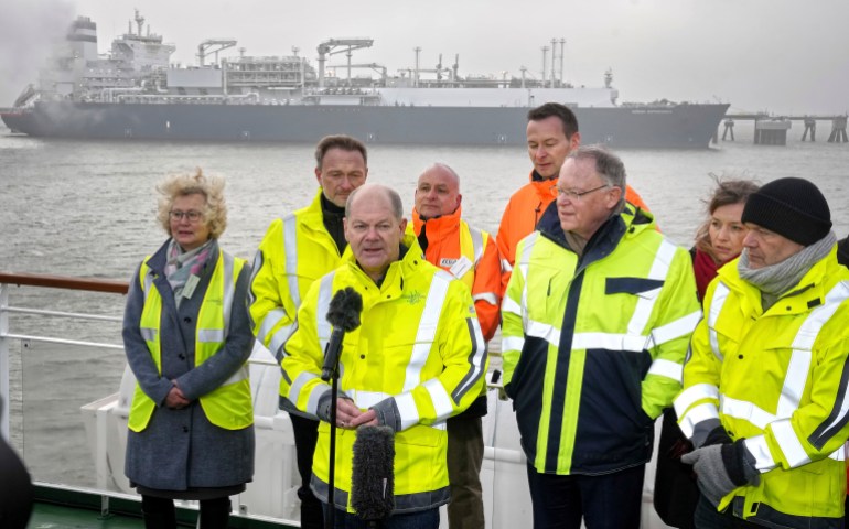 German Chancellor Olaf Scholz, front center, delivers a statement in front of the 'Hoegh Esperanza' Floating Storage and Regasification Unit (FSRU), background, during the opening of the LNG (Liquefied Natural Gas) terminal in Wilhelmshaven, Germany, Saturday, Dec. 17, 2022. (AP Photo/Michael Sohn)