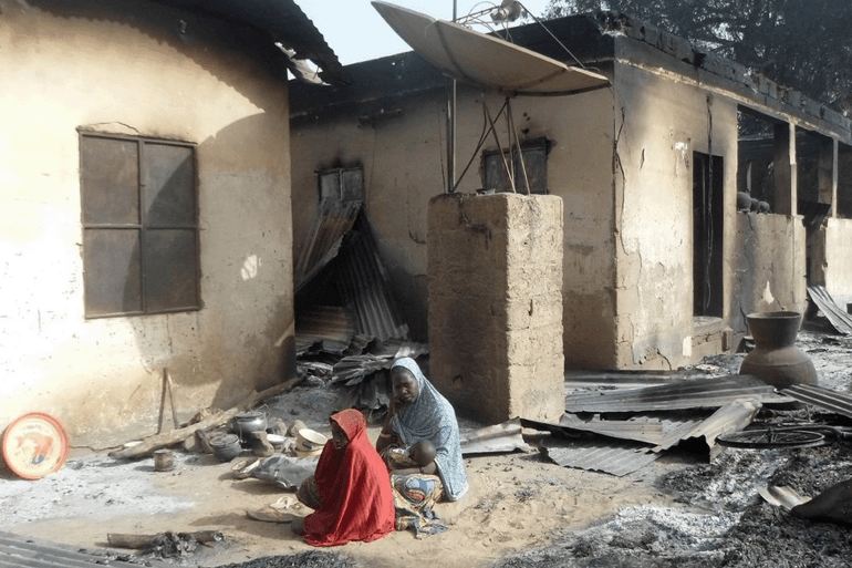 TOPSHOT-NIGERIA-UNREST-ISLAMISTS TOPSHOT - A mother sits mourning the death of her husband after Boko Haram attacks at Dalori village on the outskirts of Maiduguri in northeastern Nigeria on January 31, 2016. Around 50 people were killed when Boko Haram fighters armed with guns and explosives attacked a village in northeastern Nigeria, medics and local residents said on on January 31. Nigeria's army said the gunmen attacked Dalori just outside the northern city of Maiduguri late on January 30, burning down the village and sending residents fleeing into the bush. (Photo by STRINGER / AFP) (Photo by STRINGER/AFP via Getty Images)