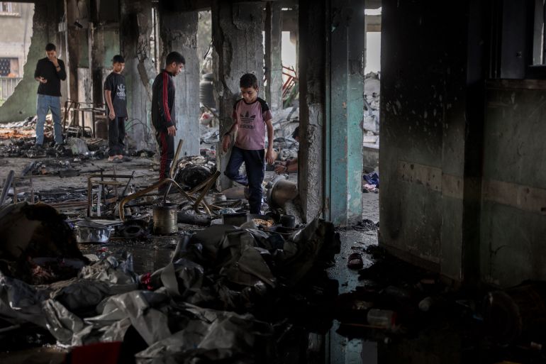 Palestinian youths look for salvageable items amid the debris after an Israeli airstrike hit the Mussa bin Nusseir UNRWA school, serving as a shelter for people who left their homes in the besieged Palestinian territory, in Gaza City's Daraj district on May 20, 2025.