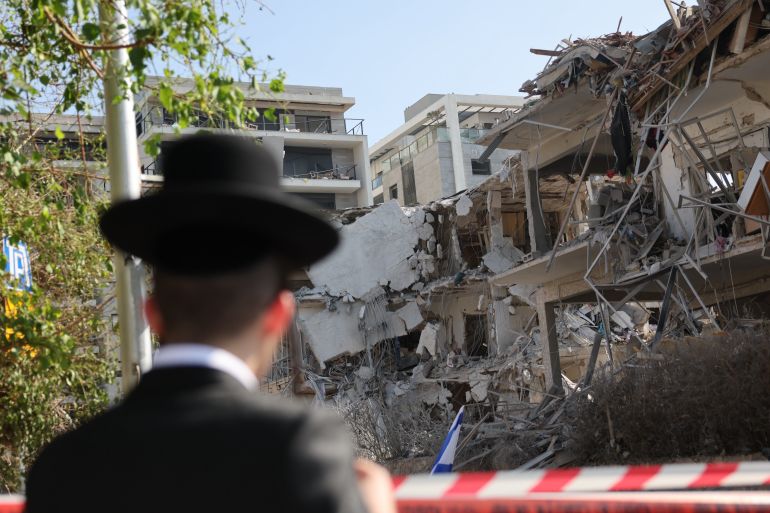epa12174616 A person stands near a damaged residential building after a ballistic missile strike in Tel Aviv, Israel, 14 June 2025. Israel's military said Iran launched dozens of missiles and drones toward Israel, with some intercepted. Magen David Adom (MDA), Israel's national emergency services, reported at least three killed and dozens of injured, including some in critical condition, in the retaliatory attacks. Israel launched strikes on Iran's nuclear and military facilities on 13 June, targeting top generals and scientists. EPA-EFE/ABIR SULTAN