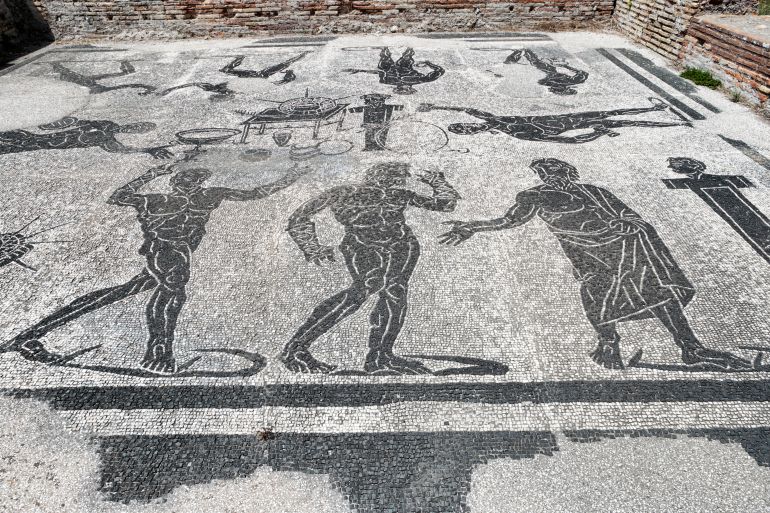 The beautiful floor mosaic of the apodytherium in the Marine Door thermal baths in Italian "Terme di Porta Marina" with a table and competition prizes