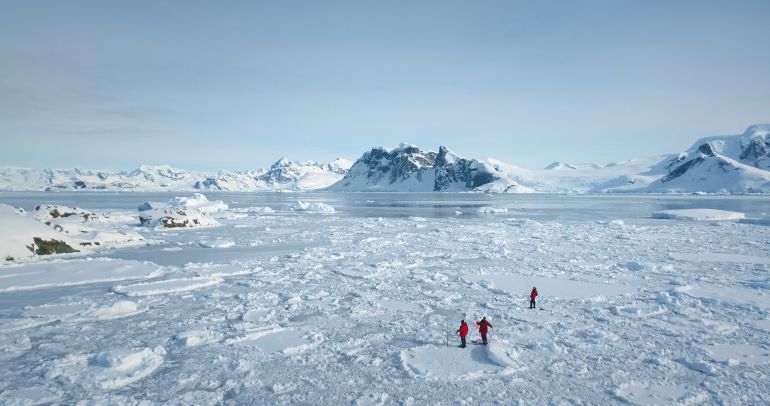 People explore Antarctica discover the beauty of South Pole. Expedition, travel and adventure in Antarctic pristine nature. Fly above frozen blue ocean panorama, glaciers and snow covered mountains