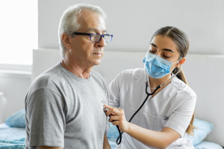 Doctor using stethoscope on a senior patient at home - إليك أسرار الكوليسترول: العدو الصامت للصحة