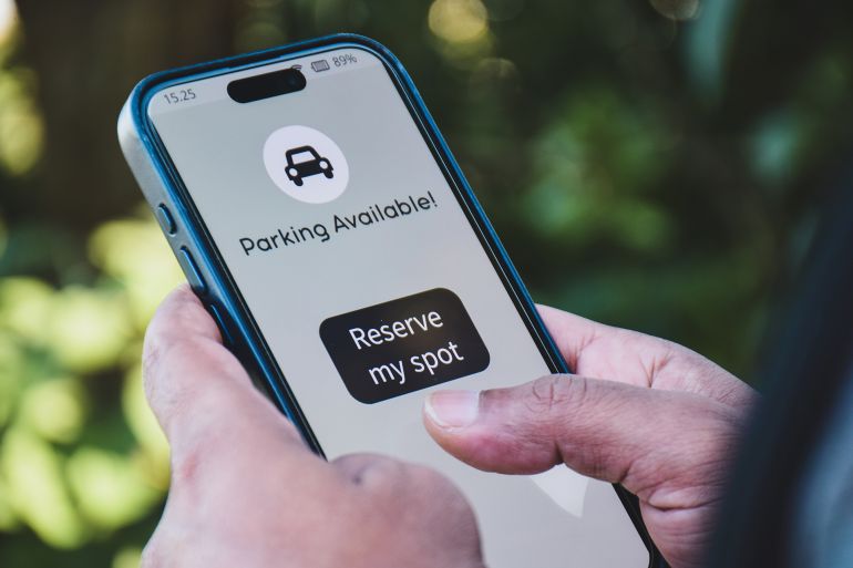 رجل يقوم بحجز مواقف لسيارته عبر الإنترنت. مفهوم نظام حجز مواقف السيارات باستخدام تطبيقات الهاتف المحمول.
